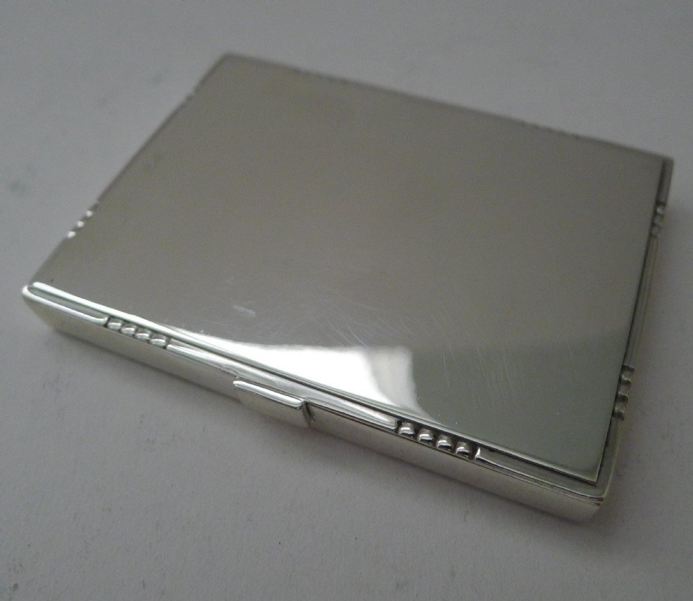 A low-profile rectangular sterling silver box with a hinged lid, polished reflective finish, and subtle beaded accents along the rim. View XII