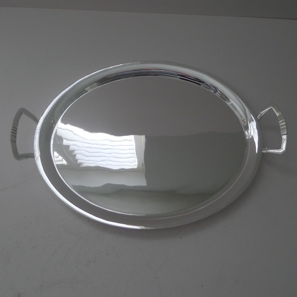 An oval silver-plated cocktail tray featuring a flat polished surface, raised rim, and two geometric angular side handles.