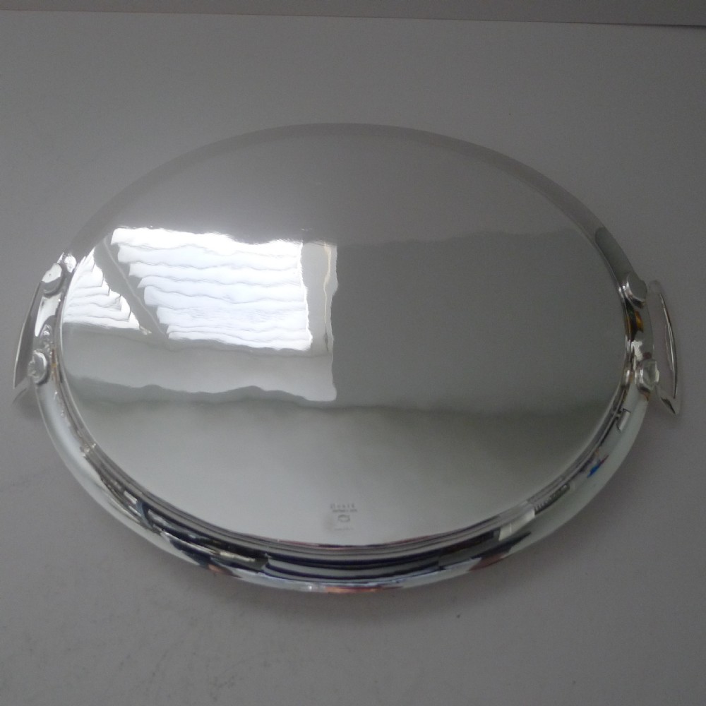 An oval silver-plated cocktail tray featuring a flat polished surface, raised rim, and two geometric angular side handles. View VII