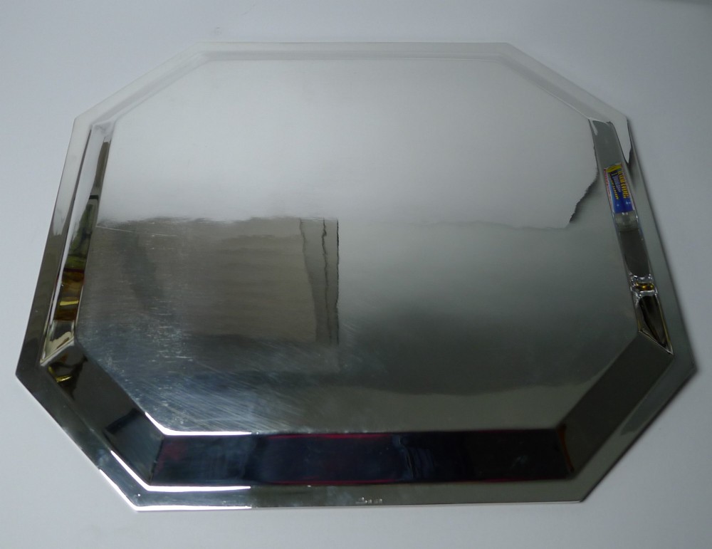 An octagonal silver-plated Art Deco tray featuring a polished reflective surface and a stepped moulded border. View VI
