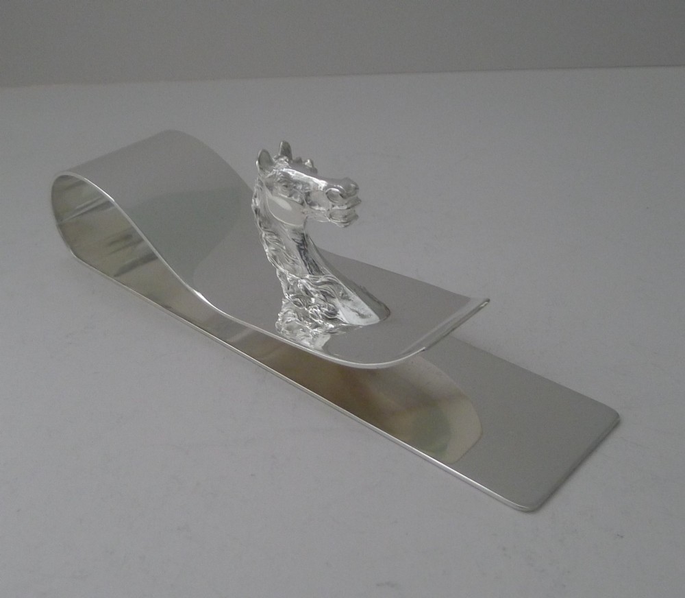A polished silver-plated bent metal desk clip featuring a detailed sculpted horse head motif.
