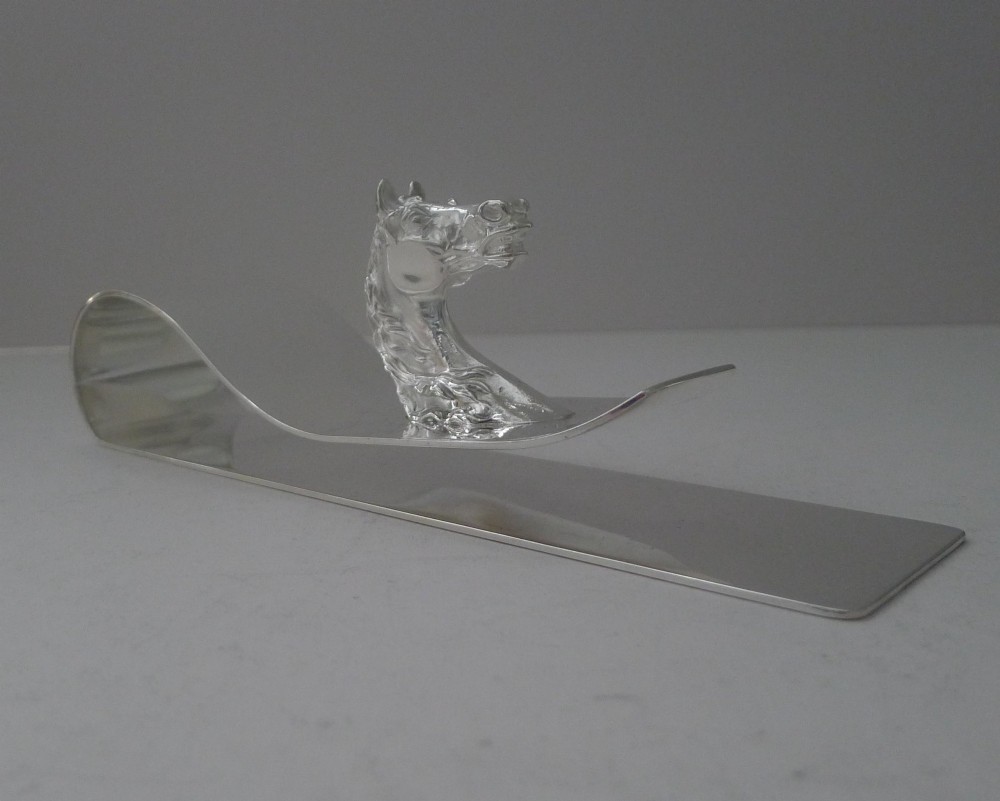 A polished silver-plated bent metal desk clip featuring a detailed sculpted horse head motif. View II