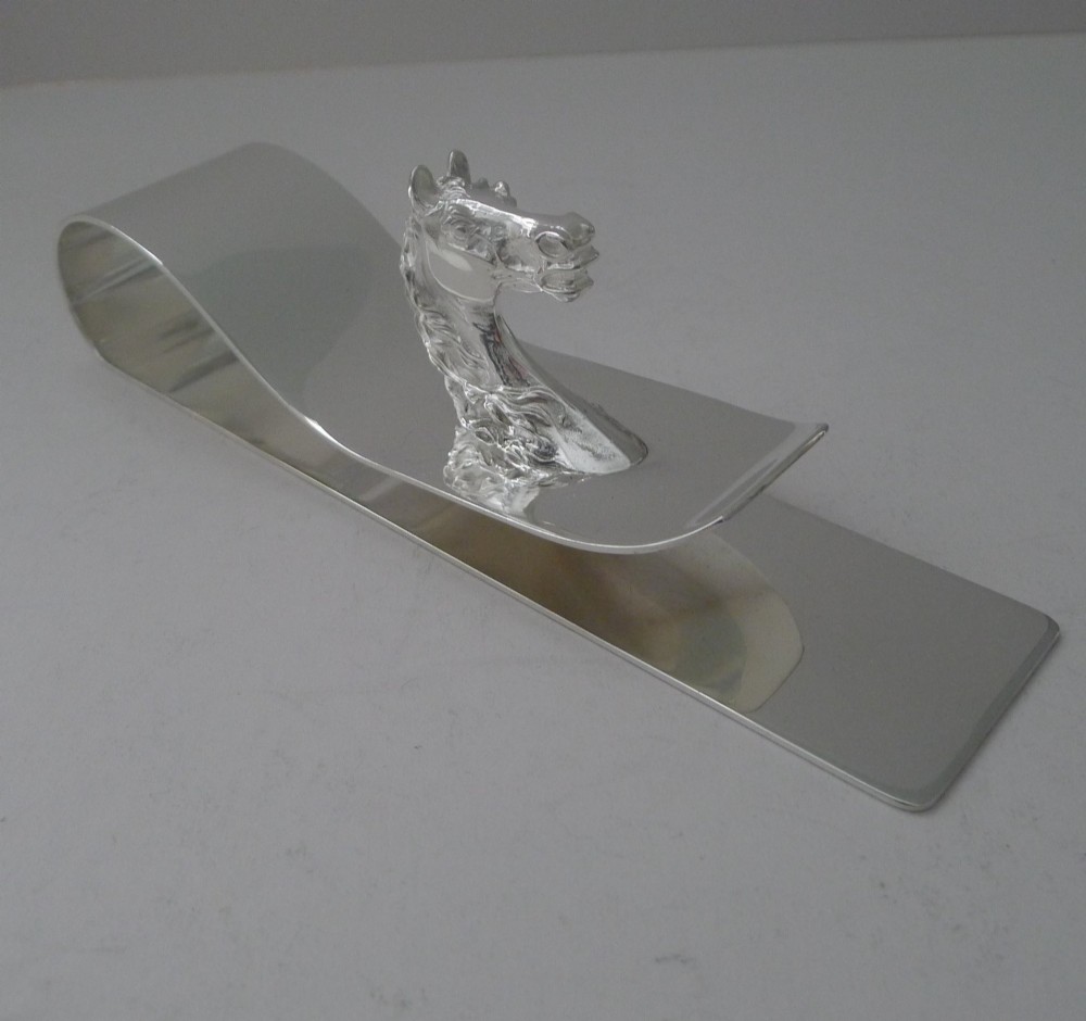 A polished silver-plated bent metal desk clip featuring a detailed sculpted horse head motif. View III
