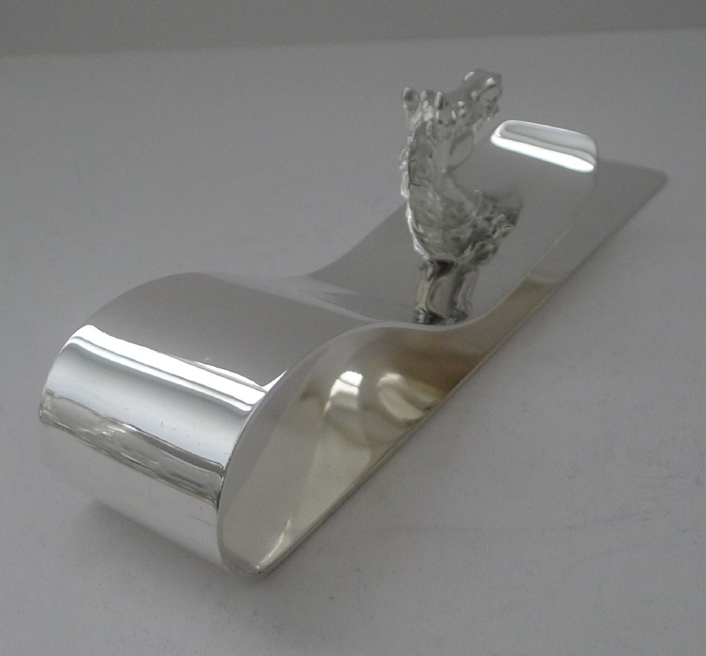 A polished silver-plated bent metal desk clip featuring a detailed sculpted horse head motif. View V