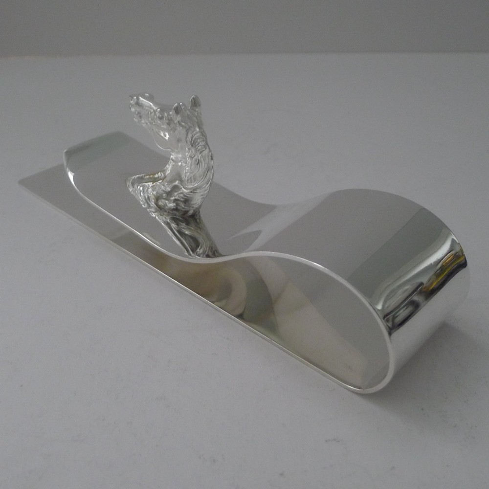 A polished silver-plated bent metal desk clip featuring a detailed sculpted horse head motif. View VI