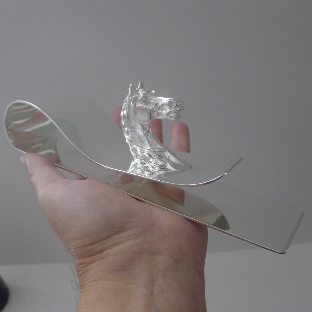 A polished silver-plated bent metal desk clip featuring a detailed sculpted horse head motif. View XI