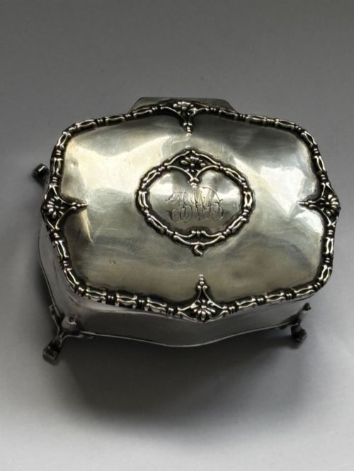 fig 1. An open George V sterling silver trinket box featuring green velvet lining, gilt lid interior, and cabriole feet.