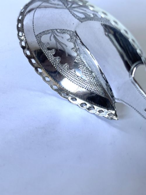 fig 1. A Georgian sterling silver caddy spoon featuring a pastern hoof shaped bowl with bright-cut engraved decoration and a short handle.