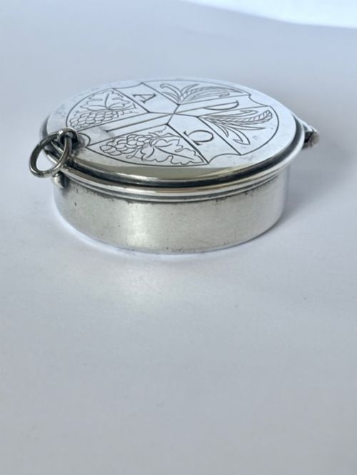 fig 1. A small round sterling silver pyx box shown open, featuring a silver exterior and a gold-gilt interior stamped with hallmarks.