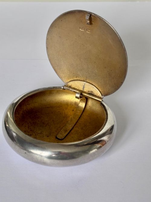 fig 1. An Edwardian oval sterling silver squeeze tobacco box with a polished finish and rounded pebble profile.