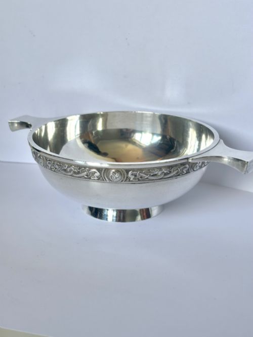 fig 1. A shallow sterling silver quaich featuring two flattened lug handles, a circular pedestal base, and a band of embossed Celtic knotwork along the upper rim.