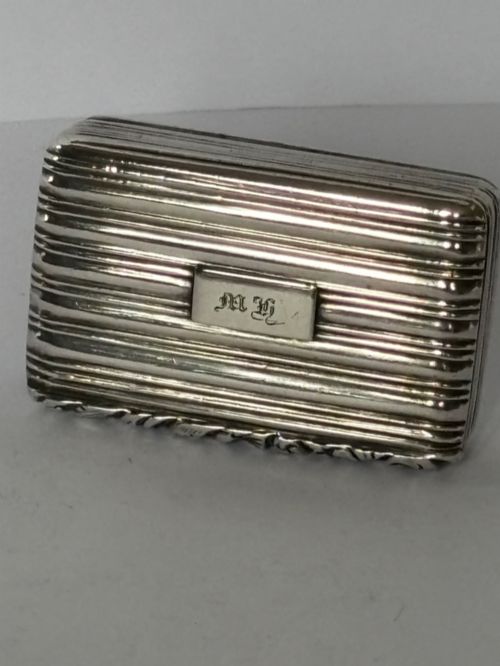 fig 1. An open George IV rectangular silver-gilt vinaigrette showing internal hallmarks and a hinged pierced grille next to a small dark sponge.