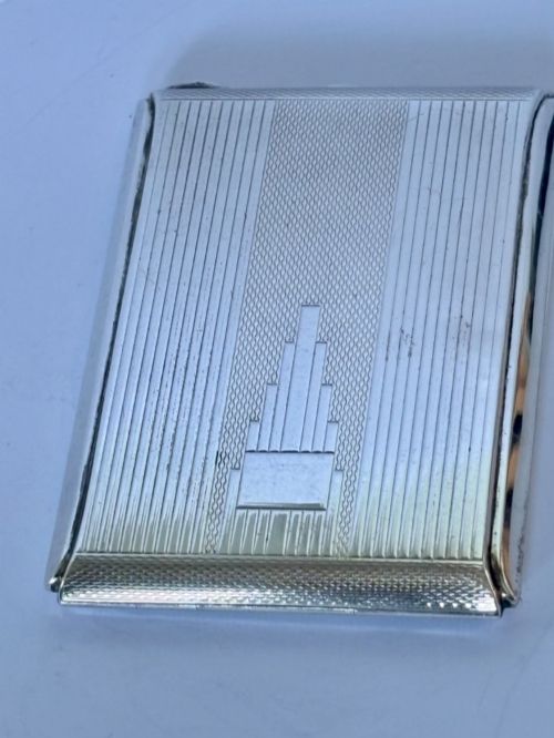 fig 1. A square sterling silver Art Deco powder compact featuring linear engine-turned patterns and a central geometric stepped motif.