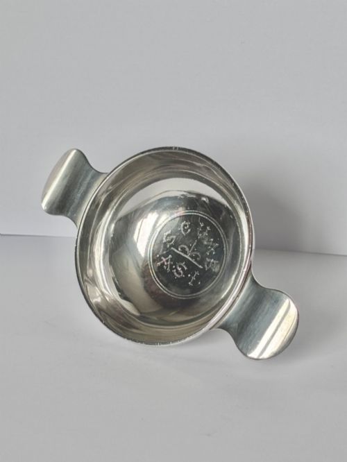 fig 1. A shallow sterling silver Scottish quaich featuring two flat lug handles and engraved Gaelic lettering in the centre bowl.