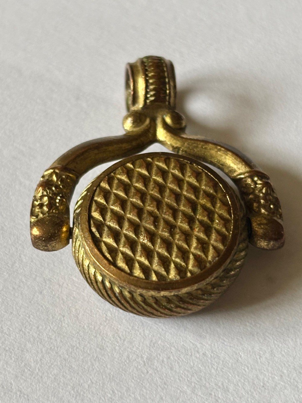 An antique Victorian gilt metal swivel compass fob pendant featuring a textured suspension arch, a rope-twist border, and a compass dial beneath glass. View III