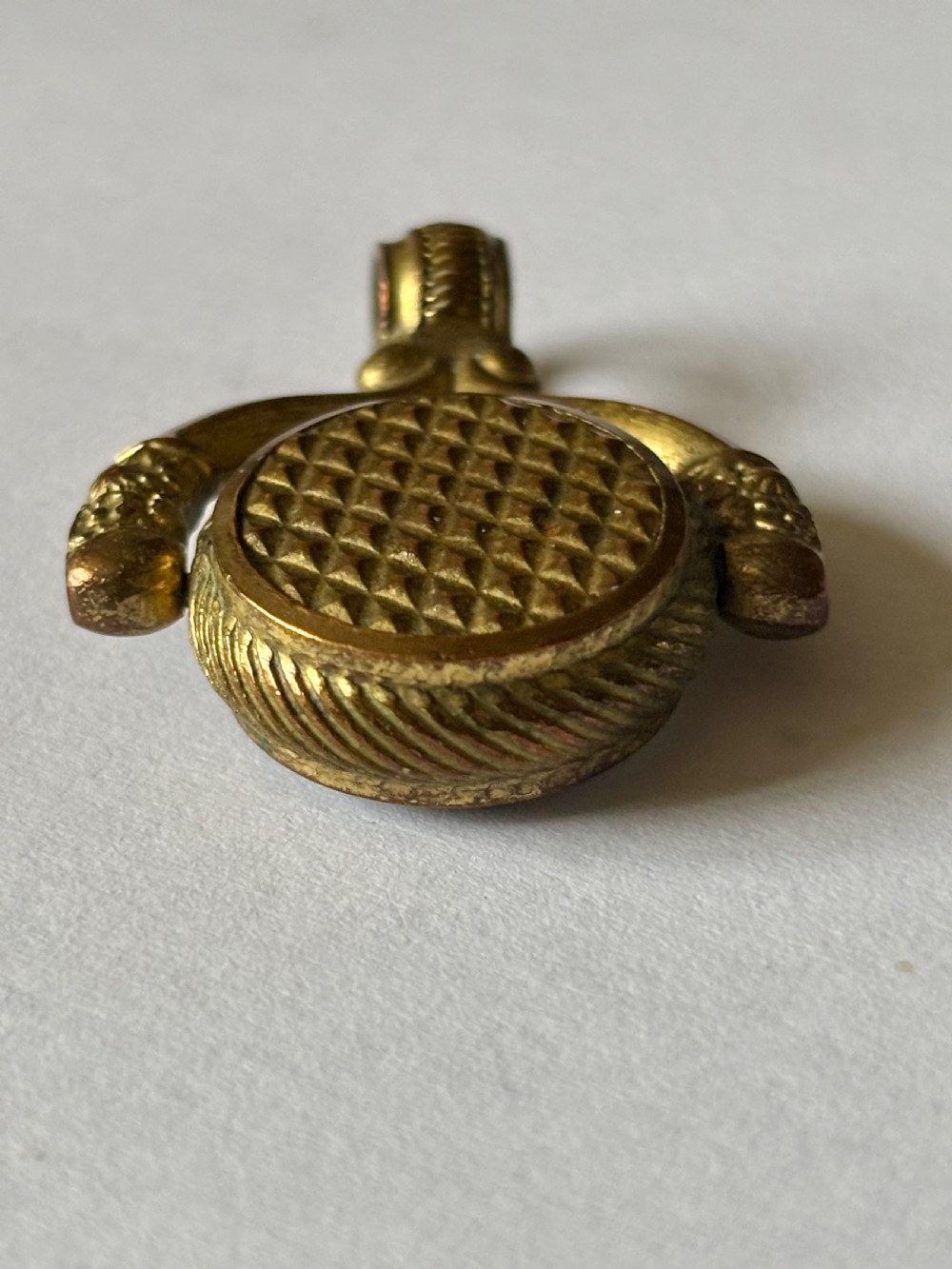 An antique Victorian gilt metal swivel compass fob pendant featuring a textured suspension arch, a rope-twist border, and a compass dial beneath glass. View IX