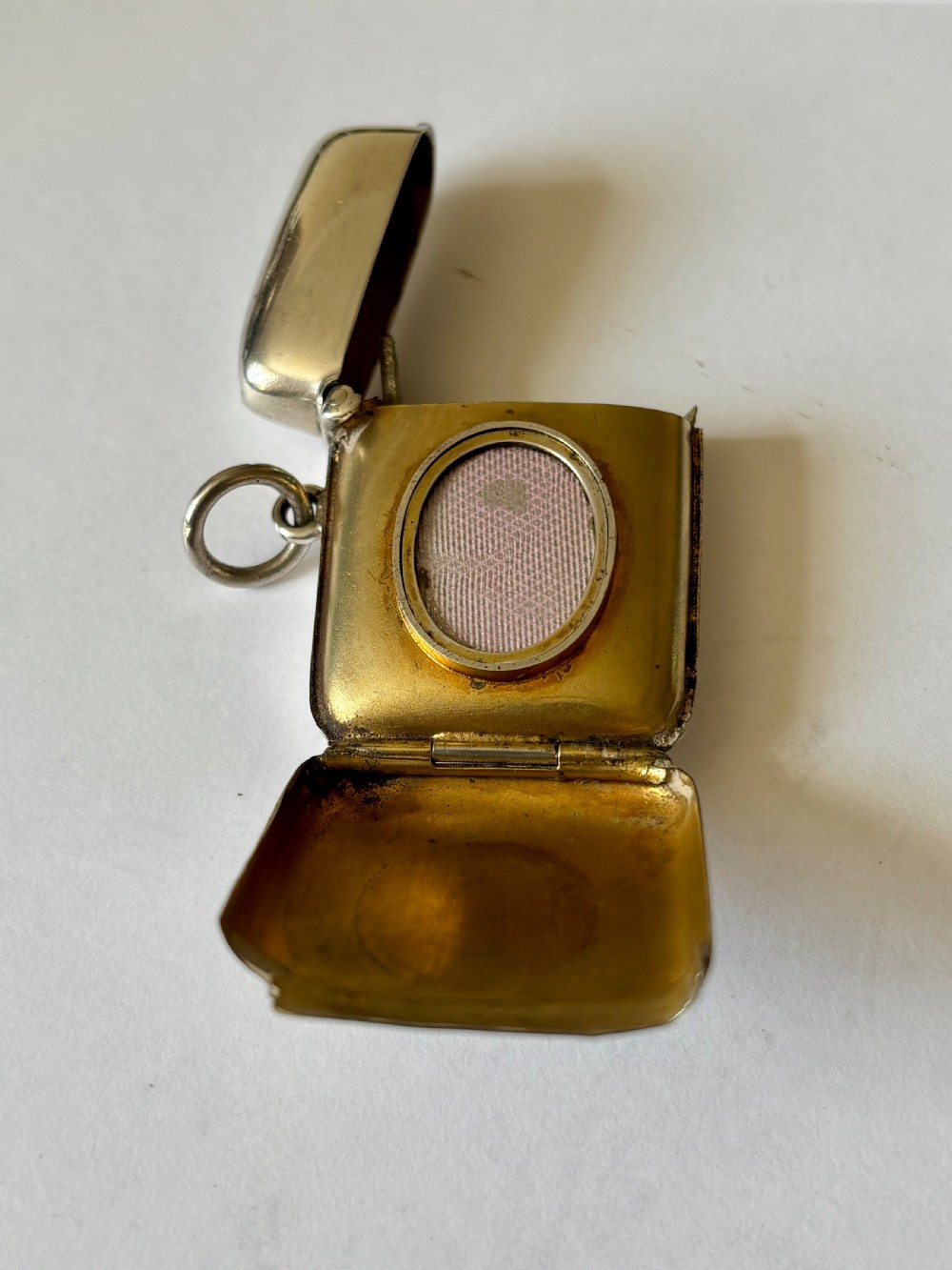 An opened Victorian sterling silver vesta case with an integrated oval photo frame, showing hinged covers and an interior gold wash.