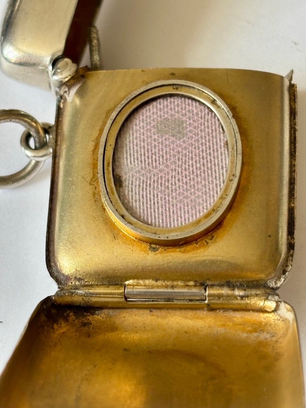 An opened Victorian sterling silver vesta case with an integrated oval photo frame, showing hinged covers and an interior gold wash. View II