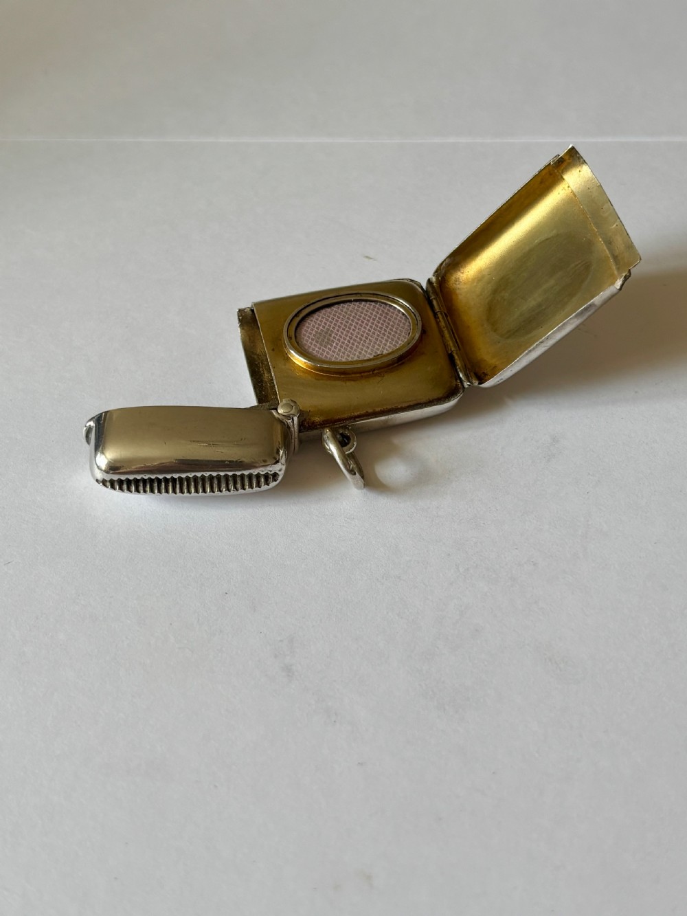 An opened Victorian sterling silver vesta case with an integrated oval photo frame, showing hinged covers and an interior gold wash. View V