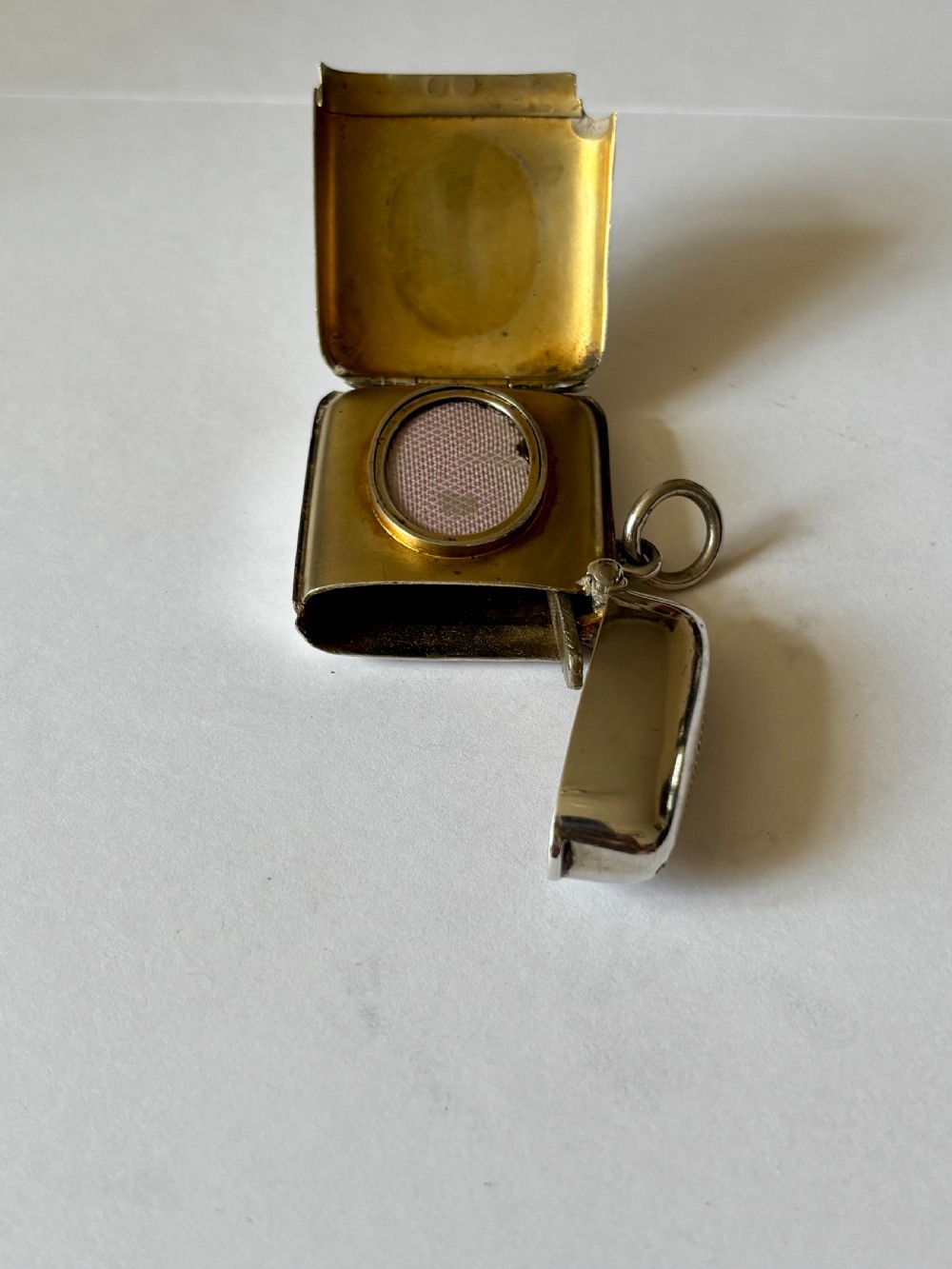An opened Victorian sterling silver vesta case with an integrated oval photo frame, showing hinged covers and an interior gold wash. View VI