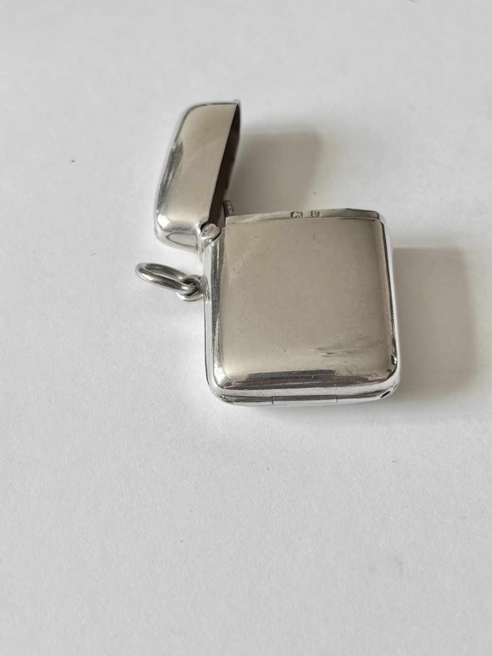 An opened Victorian sterling silver vesta case with an integrated oval photo frame, showing hinged covers and an interior gold wash. View VII