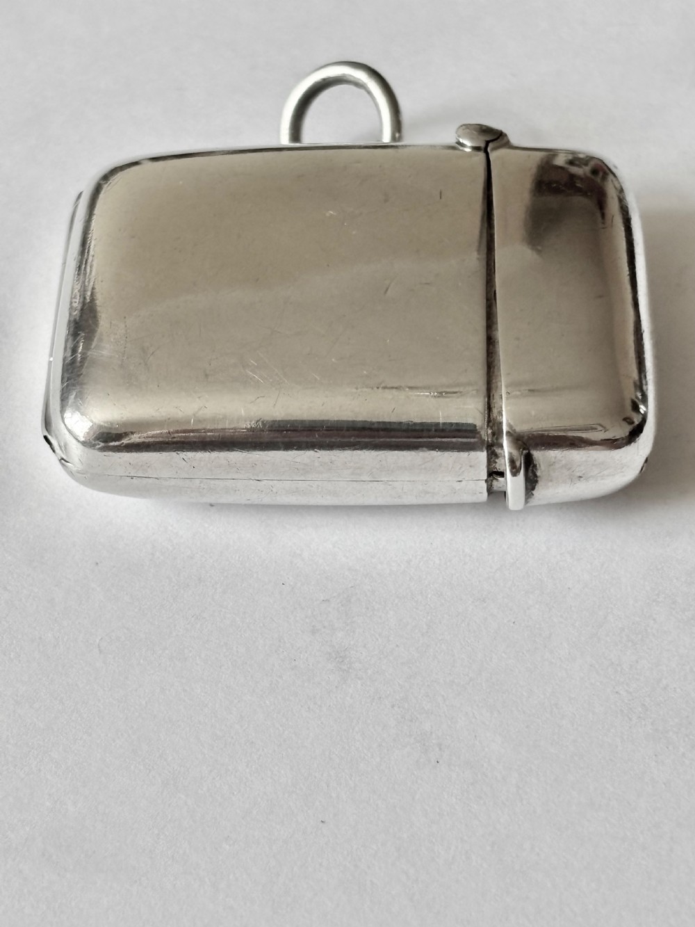 An opened Victorian sterling silver vesta case with an integrated oval photo frame, showing hinged covers and an interior gold wash. View XI