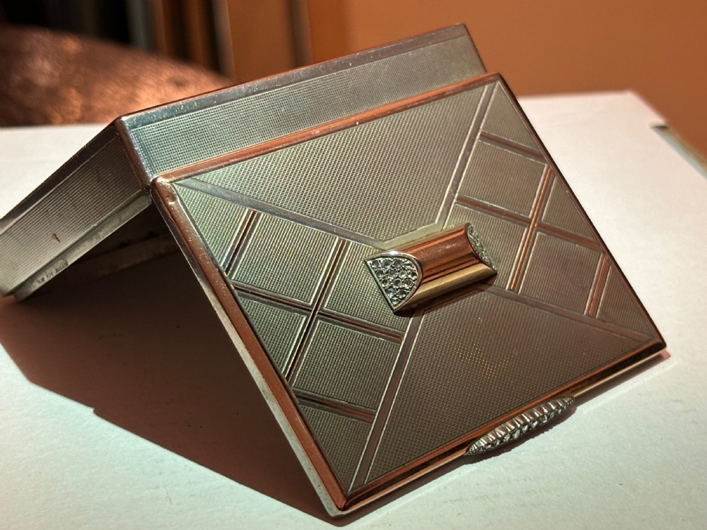 A square Art Deco rose gold vanity box featuring geometric engine-turned patterns and a diamond-paved catch. View II