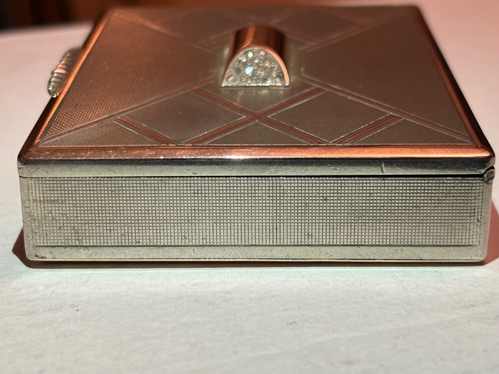 A square Art Deco rose gold vanity box featuring geometric engine-turned patterns and a diamond-paved catch. View V
