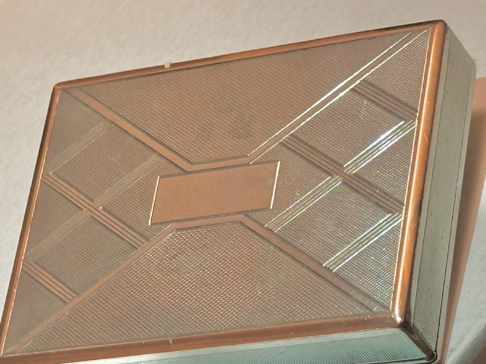 A square Art Deco rose gold vanity box featuring geometric engine-turned patterns and a diamond-paved catch. View VIII