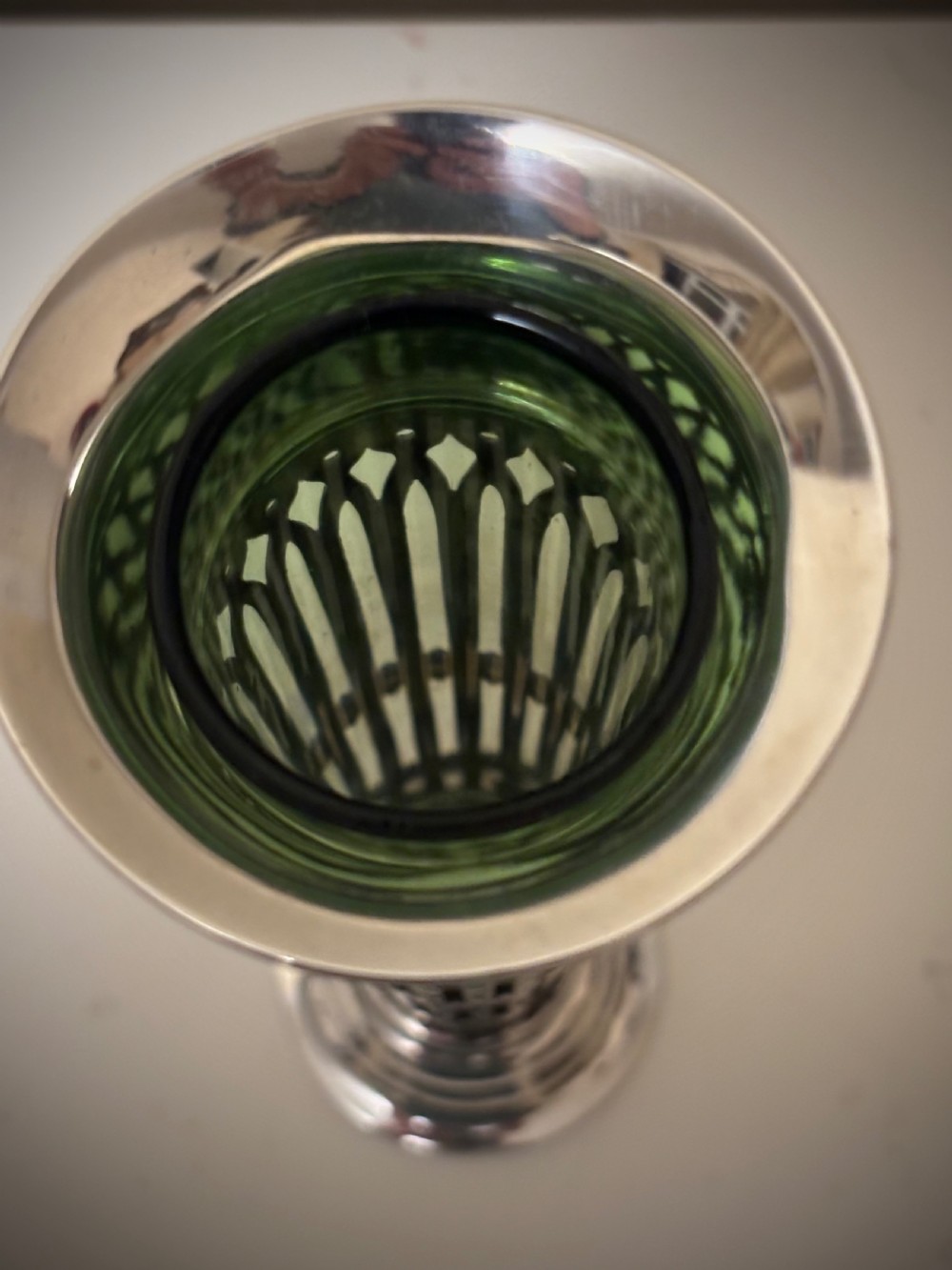Top-down view of an Edwardian pierced sterling silver vase featuring a flared rim and a dark green glass liner.
