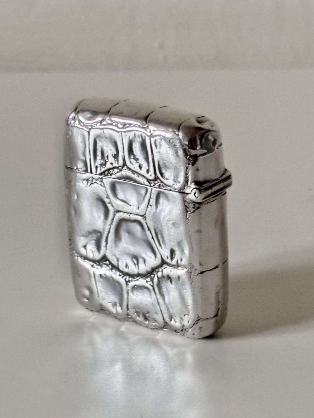 A rectangular Victorian sterling silver pocket vesta case with an embossed crocodile skin texture and hinged lid.