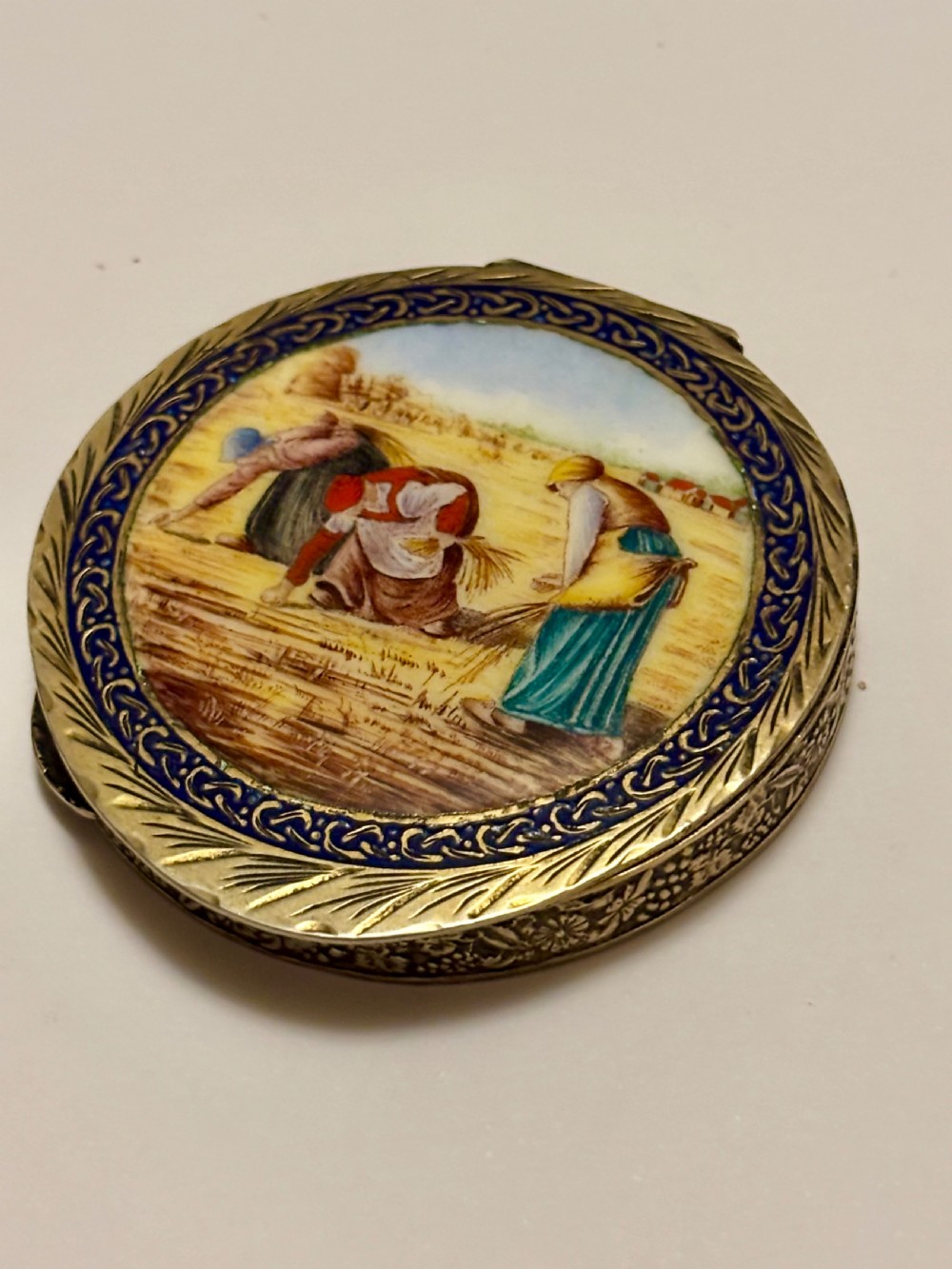 A circular vintage Italian 800 silver powder compact featuring a hand-painted enamel scene of harvest workers framed by a cobalt blue enamel border.