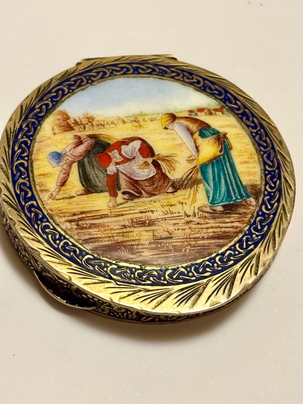 A circular vintage Italian 800 silver powder compact featuring a hand-painted enamel scene of harvest workers framed by a cobalt blue enamel border. View II