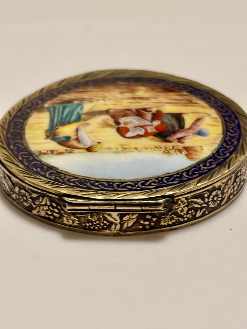A circular vintage Italian 800 silver powder compact featuring a hand-painted enamel scene of harvest workers framed by a cobalt blue enamel border. View V
