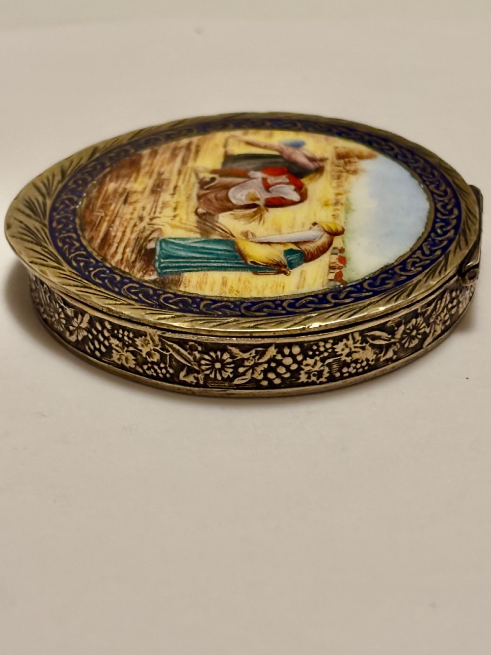 A circular vintage Italian 800 silver powder compact featuring a hand-painted enamel scene of harvest workers framed by a cobalt blue enamel border. View VI