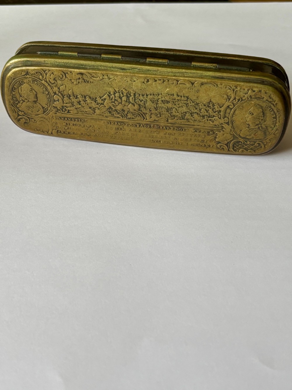 An oblong 18th-century brass and copper tobacco box featuring relief engravings of military battle scenes and portrait medallions on its lid. View III