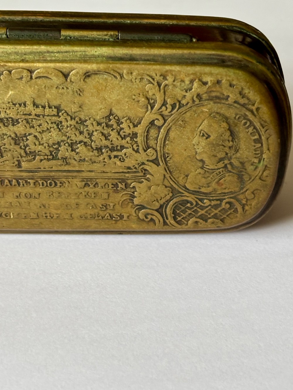 An oblong 18th-century brass and copper tobacco box featuring relief engravings of military battle scenes and portrait medallions on its lid. View VI