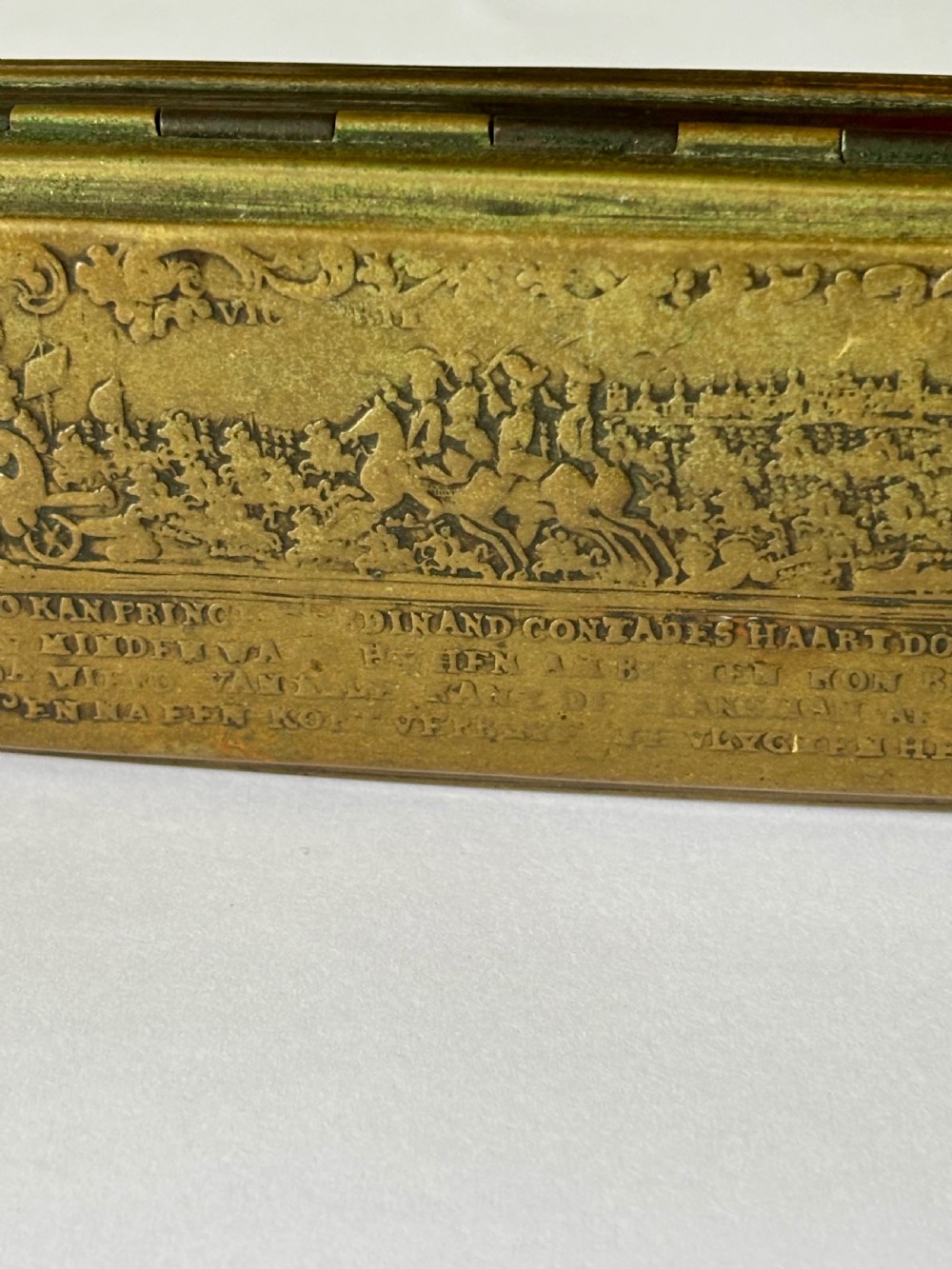 An oblong 18th-century brass and copper tobacco box featuring relief engravings of military battle scenes and portrait medallions on its lid. View VII
