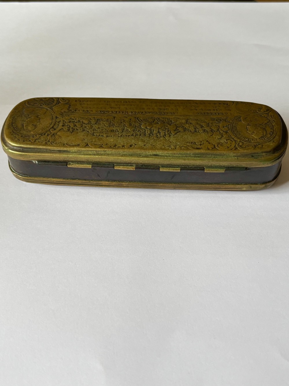 An oblong 18th-century brass and copper tobacco box featuring relief engravings of military battle scenes and portrait medallions on its lid. View VIII