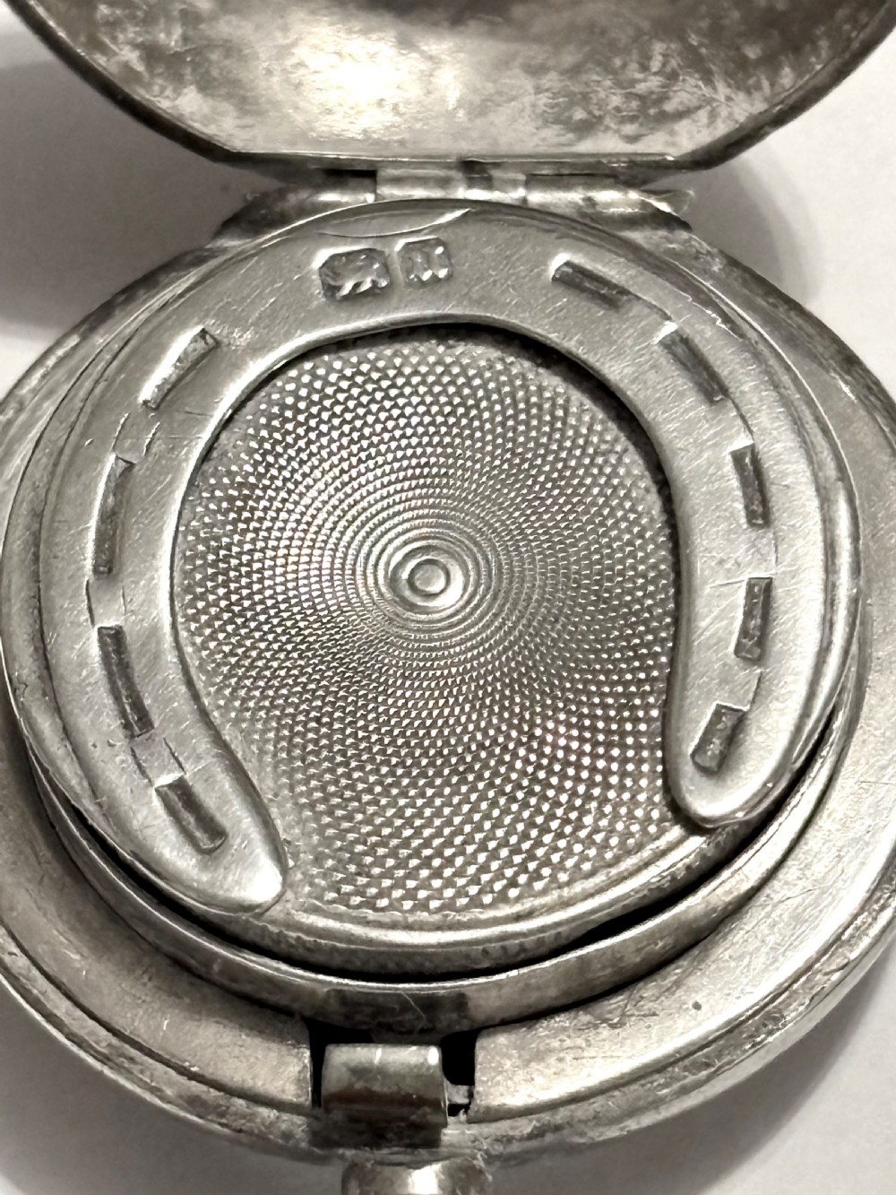 A circular Victorian sterling silver sovereign case with hand-engraved scrollwork detail and a top suspension loop. View II