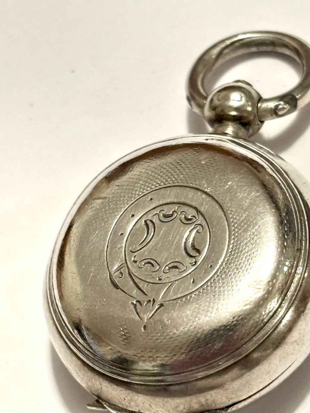 A circular Victorian sterling silver sovereign case with hand-engraved scrollwork detail and a top suspension loop. View III