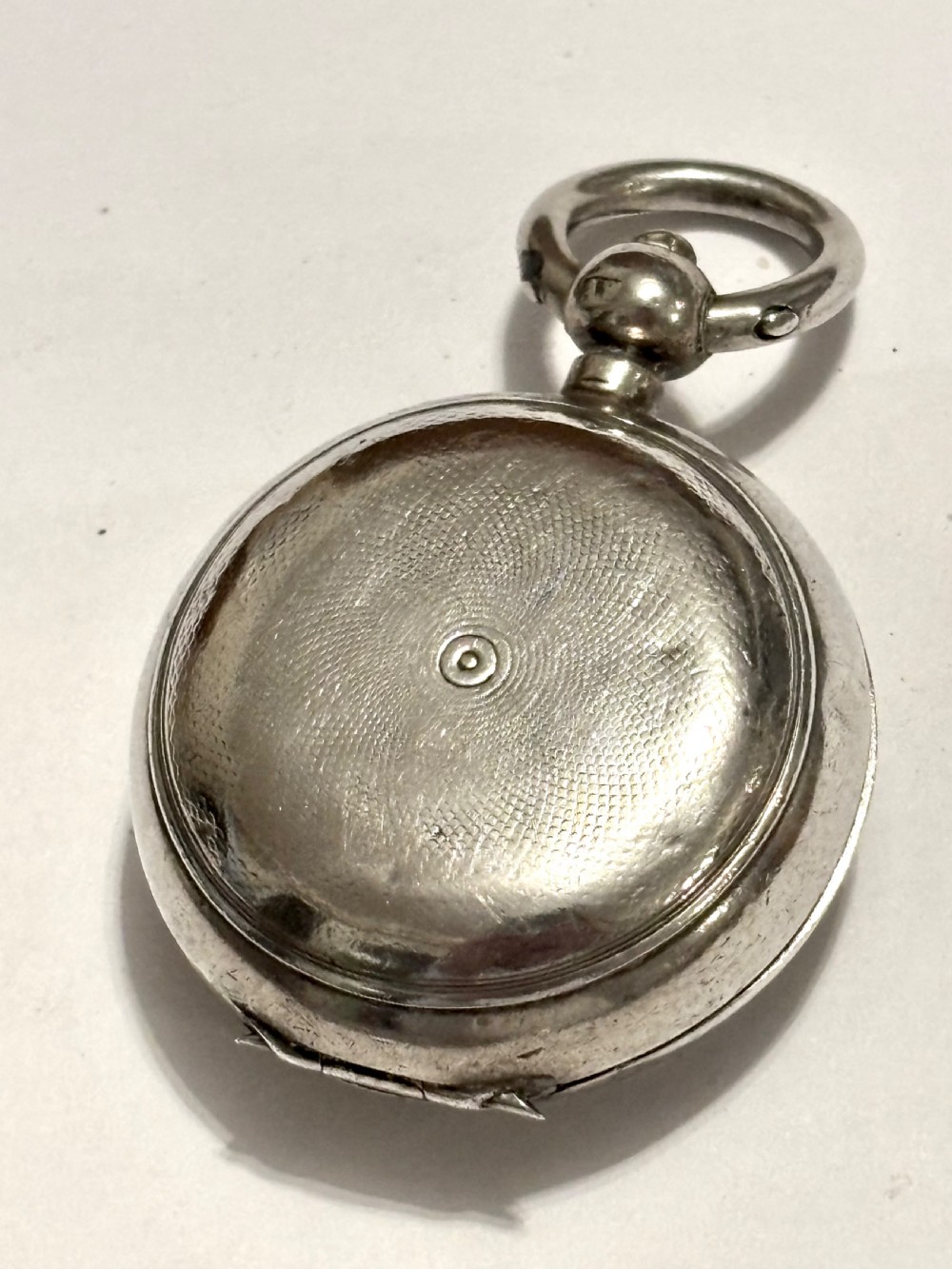 A circular Victorian sterling silver sovereign case with hand-engraved scrollwork detail and a top suspension loop. View V