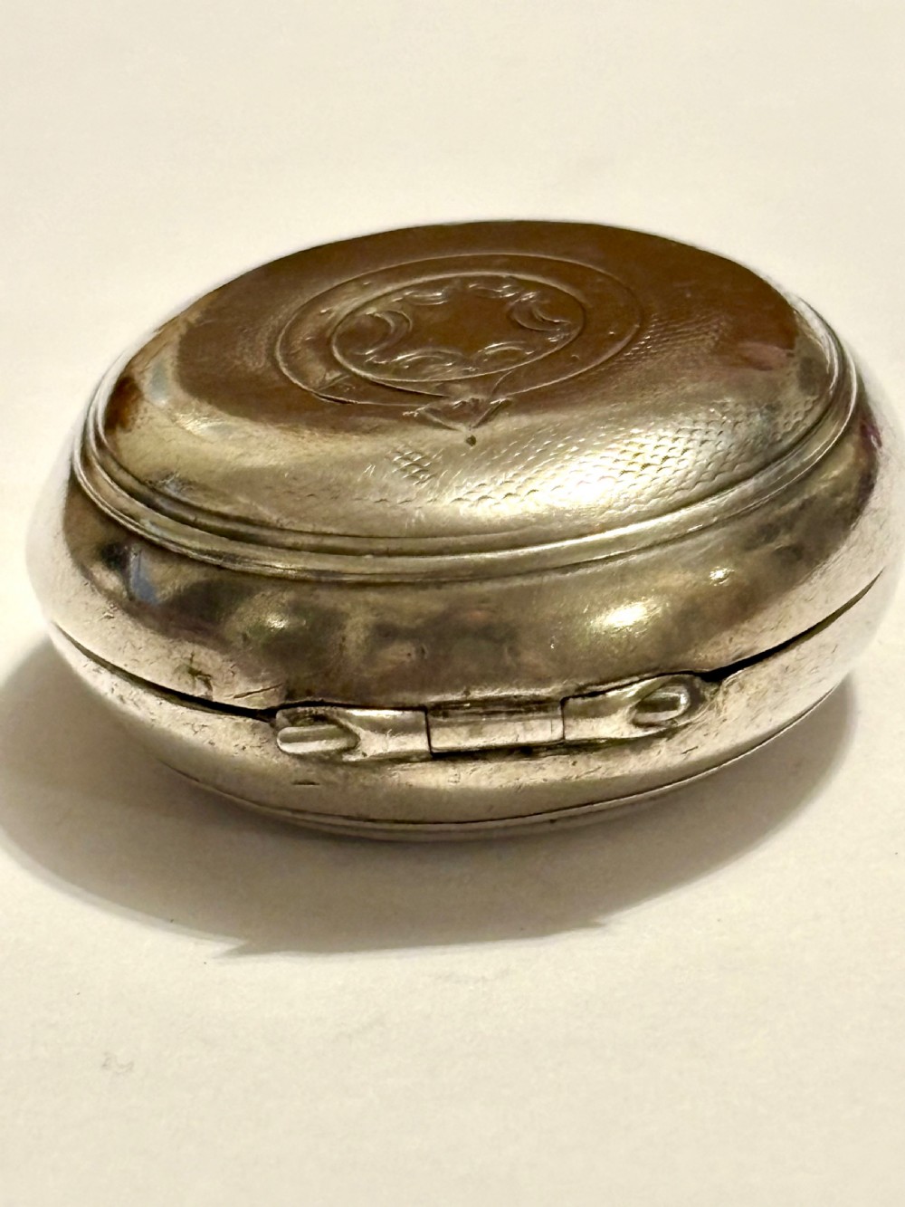 A circular Victorian sterling silver sovereign case with hand-engraved scrollwork detail and a top suspension loop. View VI