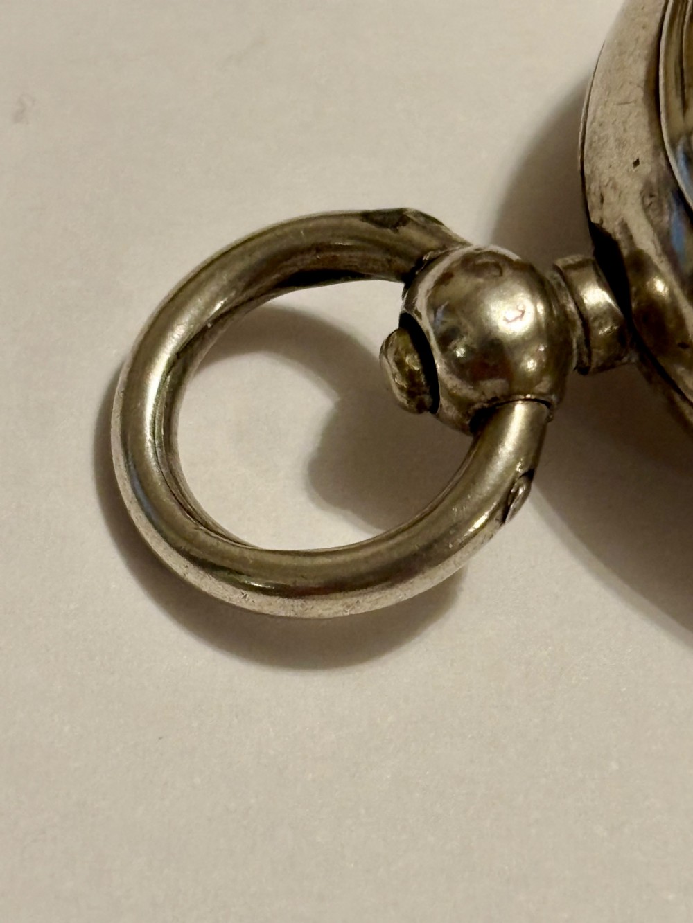A circular Victorian sterling silver sovereign case with hand-engraved scrollwork detail and a top suspension loop. View VII
