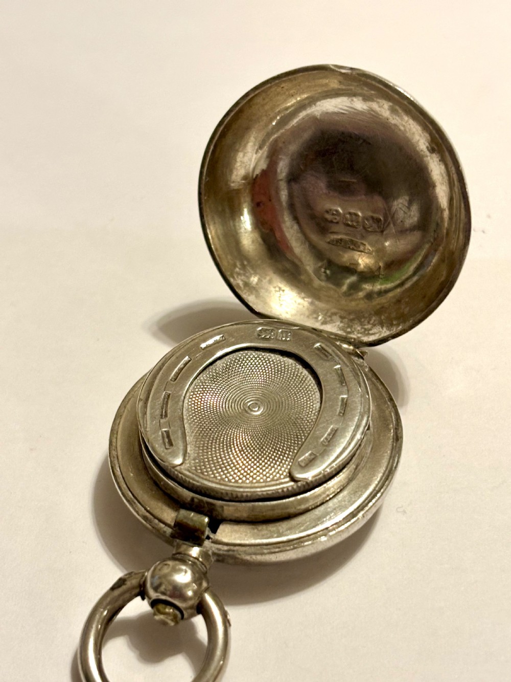 A circular Victorian sterling silver sovereign case with hand-engraved scrollwork detail and a top suspension loop. View VIII