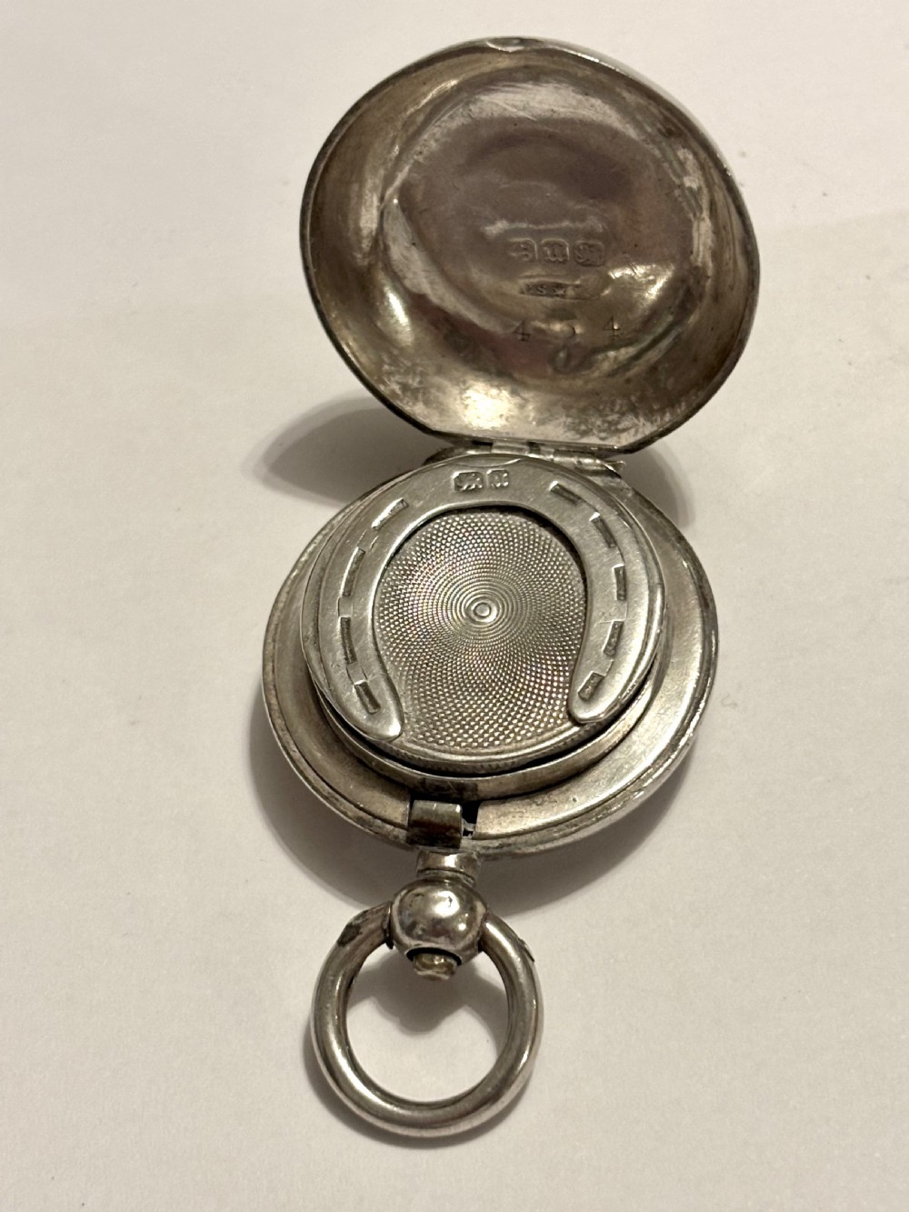 A circular Victorian sterling silver sovereign case with hand-engraved scrollwork detail and a top suspension loop. View IX