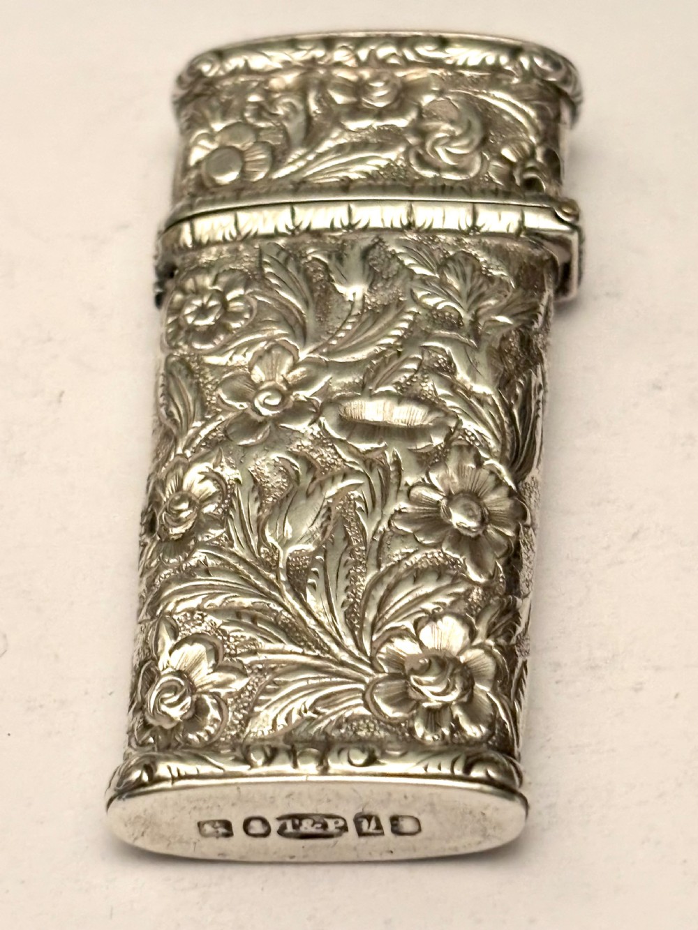An open William IV sterling silver fleam case with floral chasing, revealing two dark-handled folding blades inside. View III