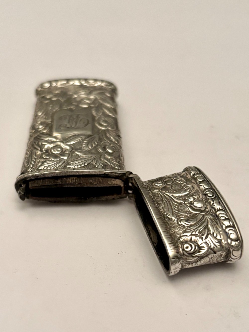 An open William IV sterling silver fleam case with floral chasing, revealing two dark-handled folding blades inside. View V
