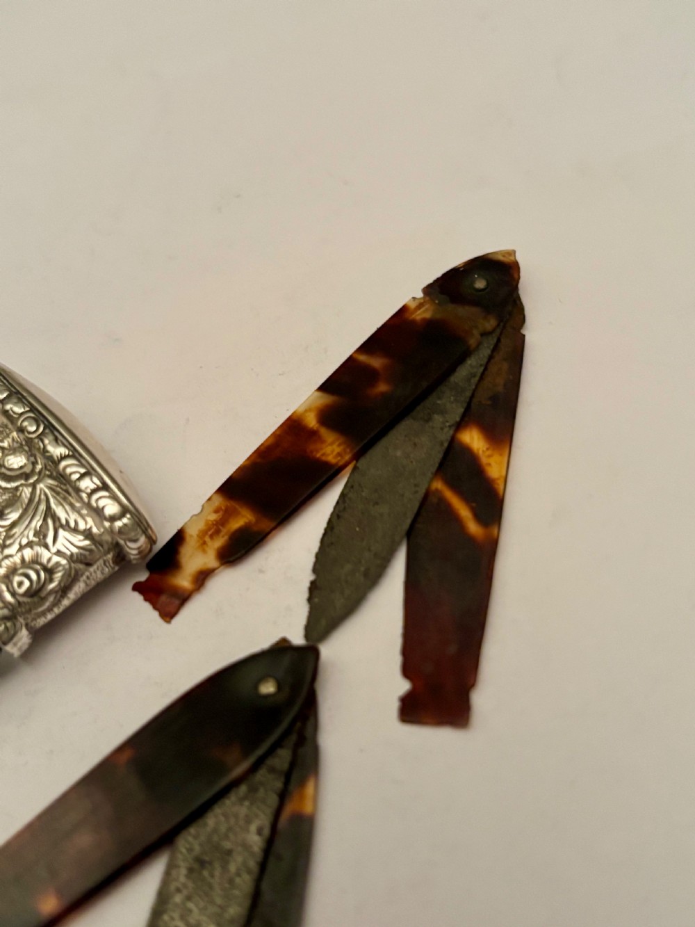 An open William IV sterling silver fleam case with floral chasing, revealing two dark-handled folding blades inside. View XIII