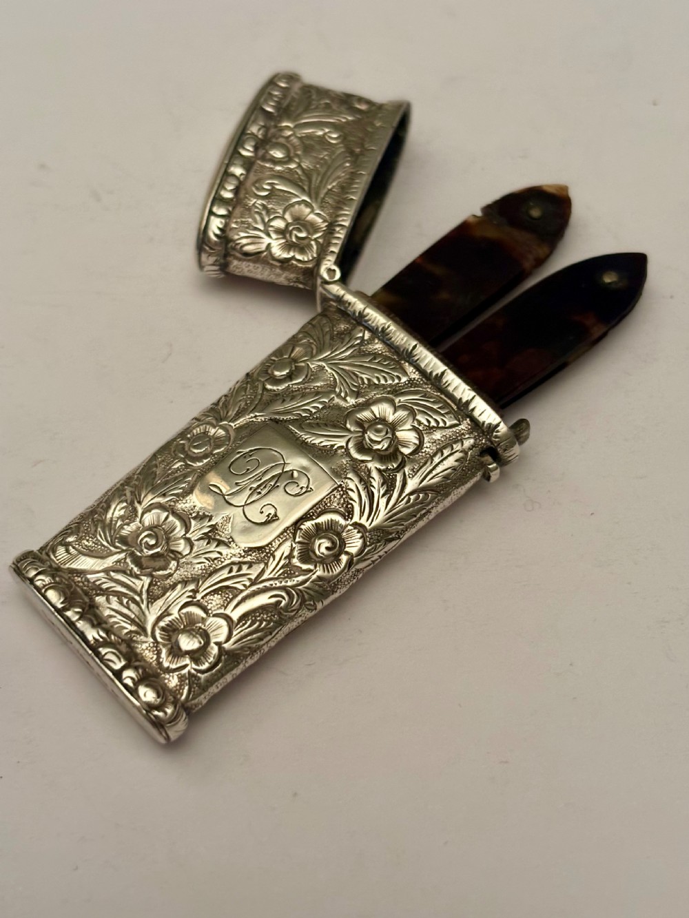 An open William IV sterling silver fleam case with floral chasing, revealing two dark-handled folding blades inside. View XIV